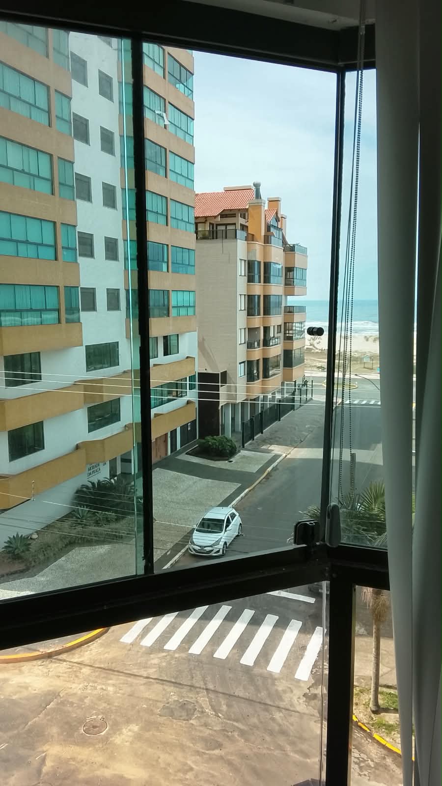 Varanda envidraçada com perfil de alumínio preto e vista panorâmica para a praia